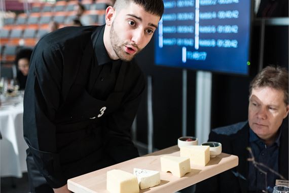 Tarjoilija esittelee juustotarjottimen